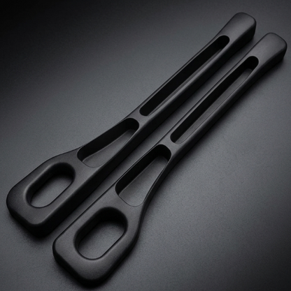 Two matte black ergonomic handles with integrated cutouts, photographed on a dark gradient studio background.