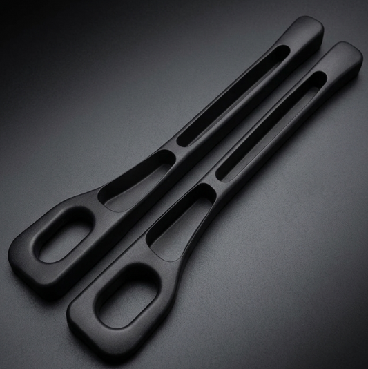 Two matte black ergonomic handles with integrated cutouts, photographed on a dark gradient studio background.